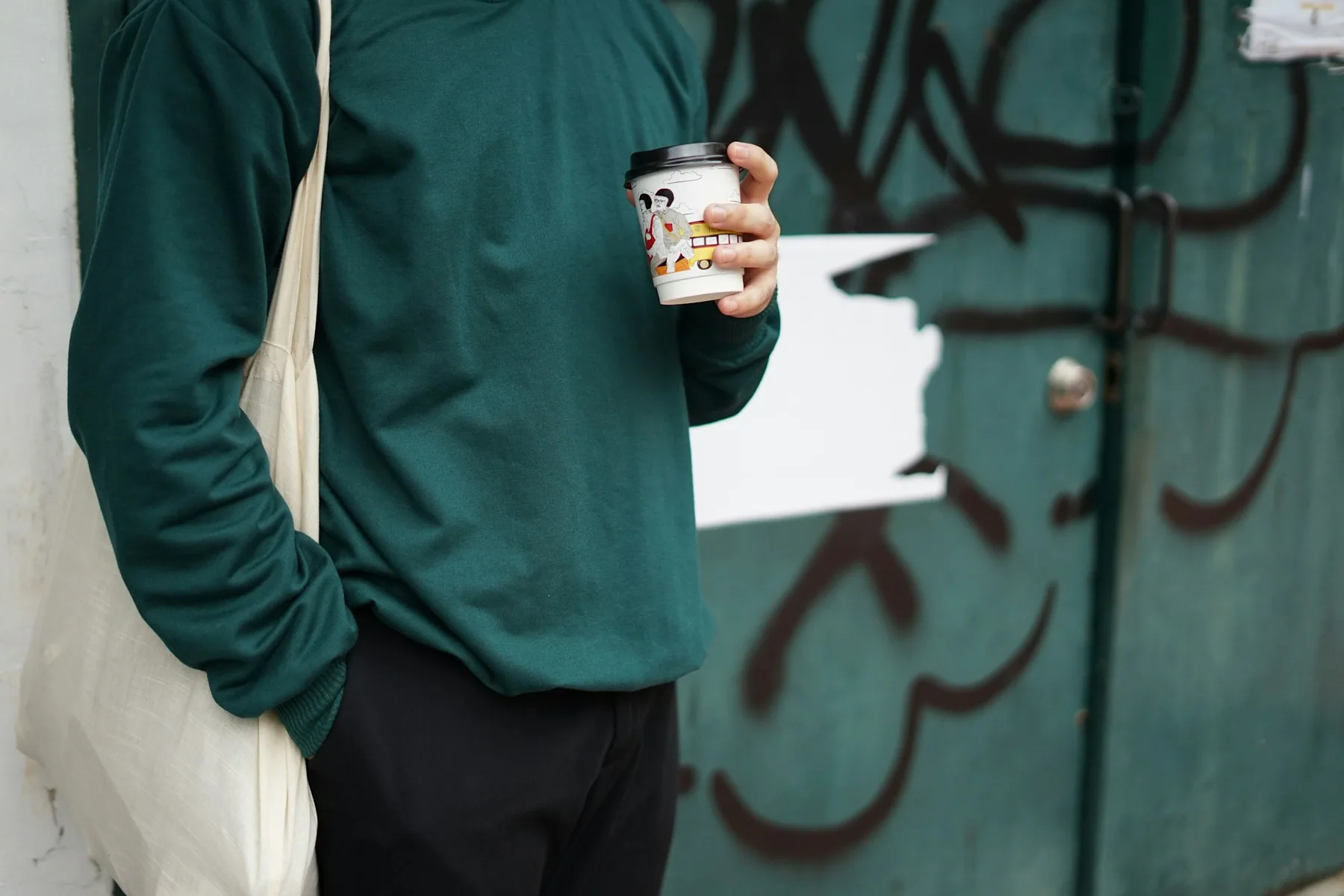 Man in a sweatshirt holding a coffee cup outdoors