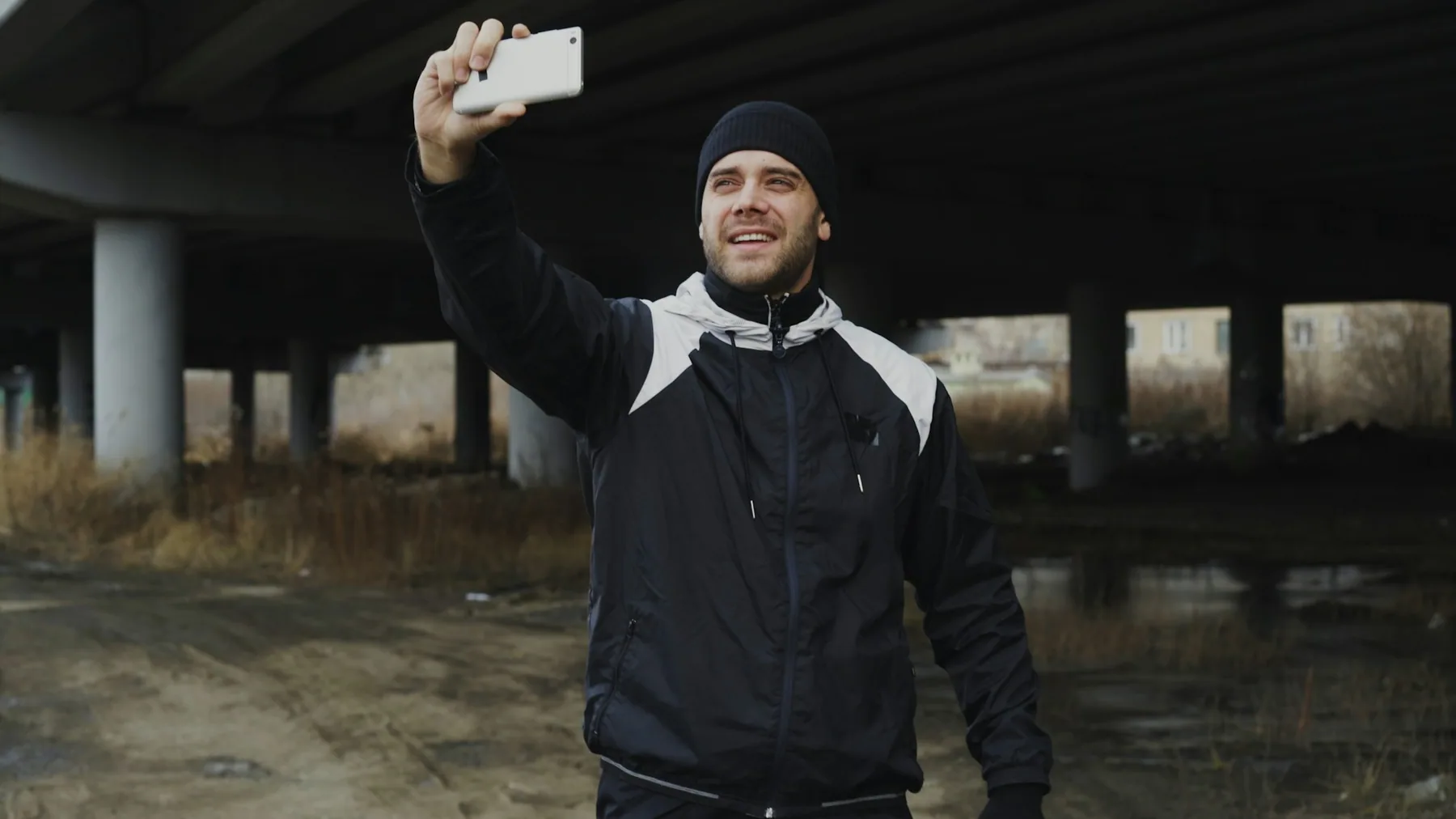 Man in a dark jacket walking under an overpass