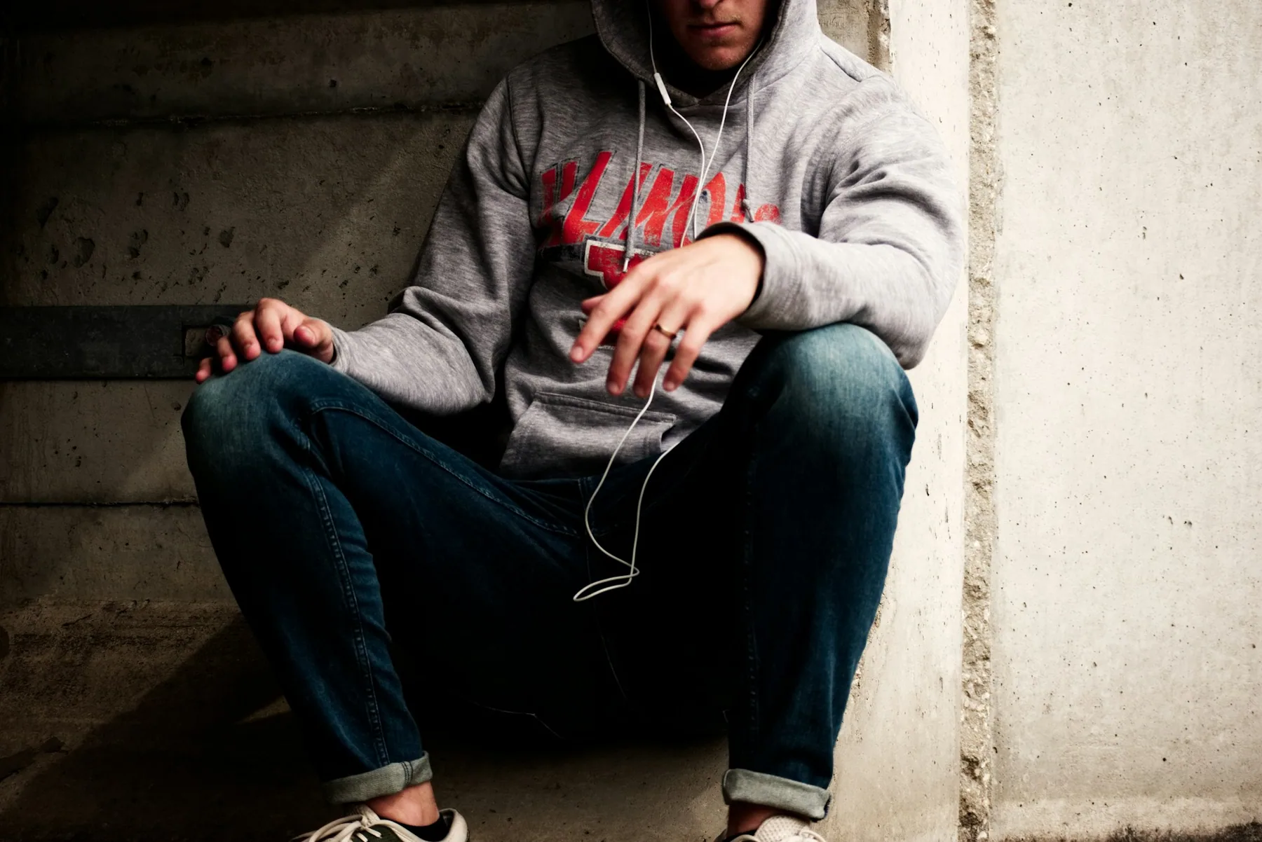 Man in a grey hooded top sitting outdoors