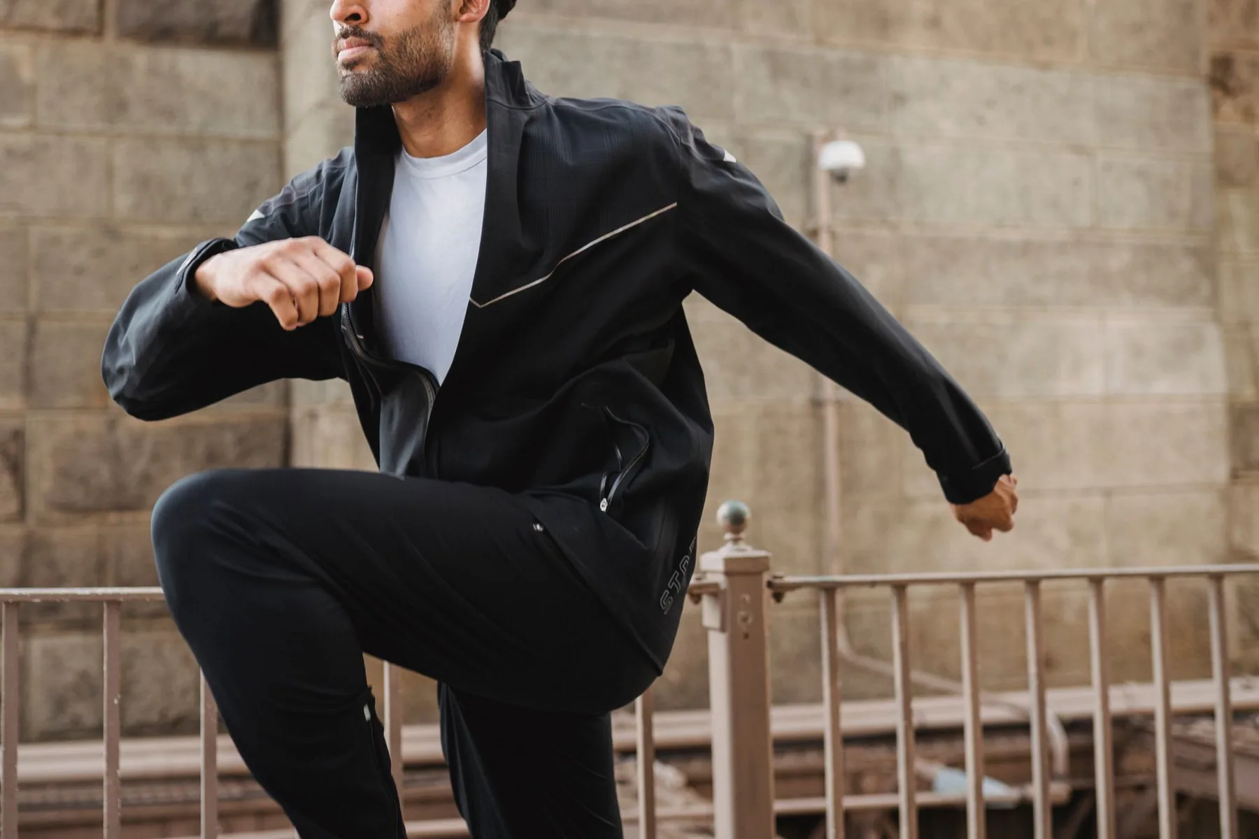 Man in dark sportswear mid-stride in a city