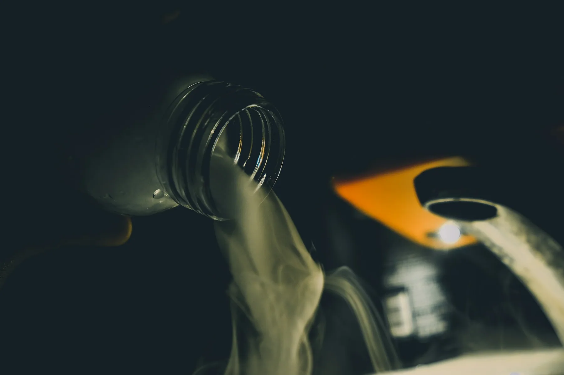 Liquid detergent being poured, lit against a dark background