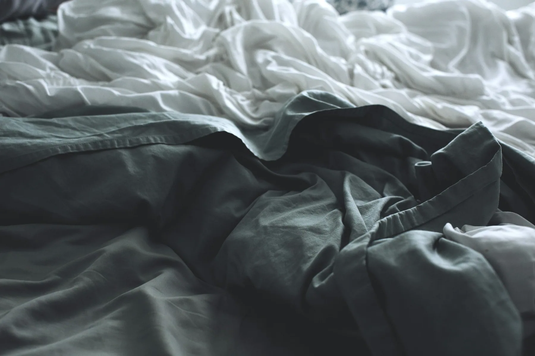 A dark garment lying on grey bedding