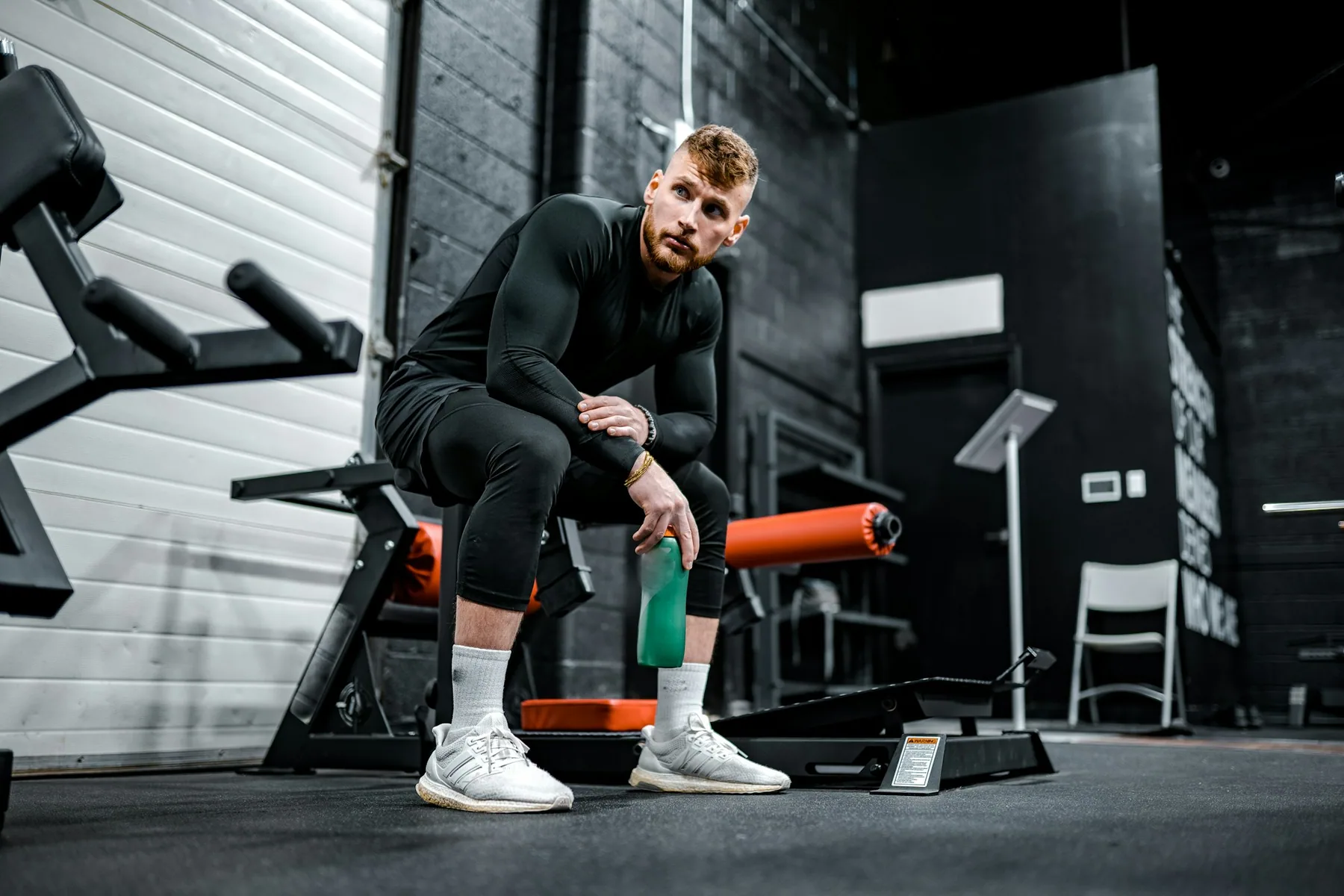 Someone sitting on a bench in plain black training kit