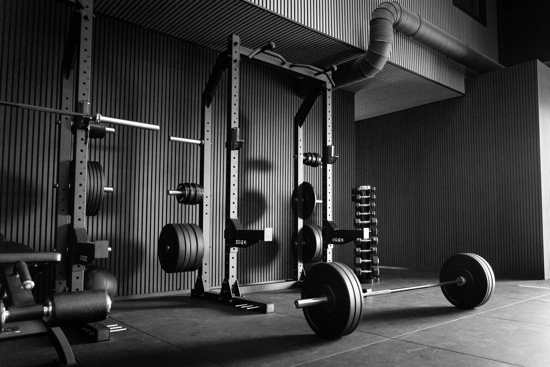 A squat rack and loaded barbell in a dark gym