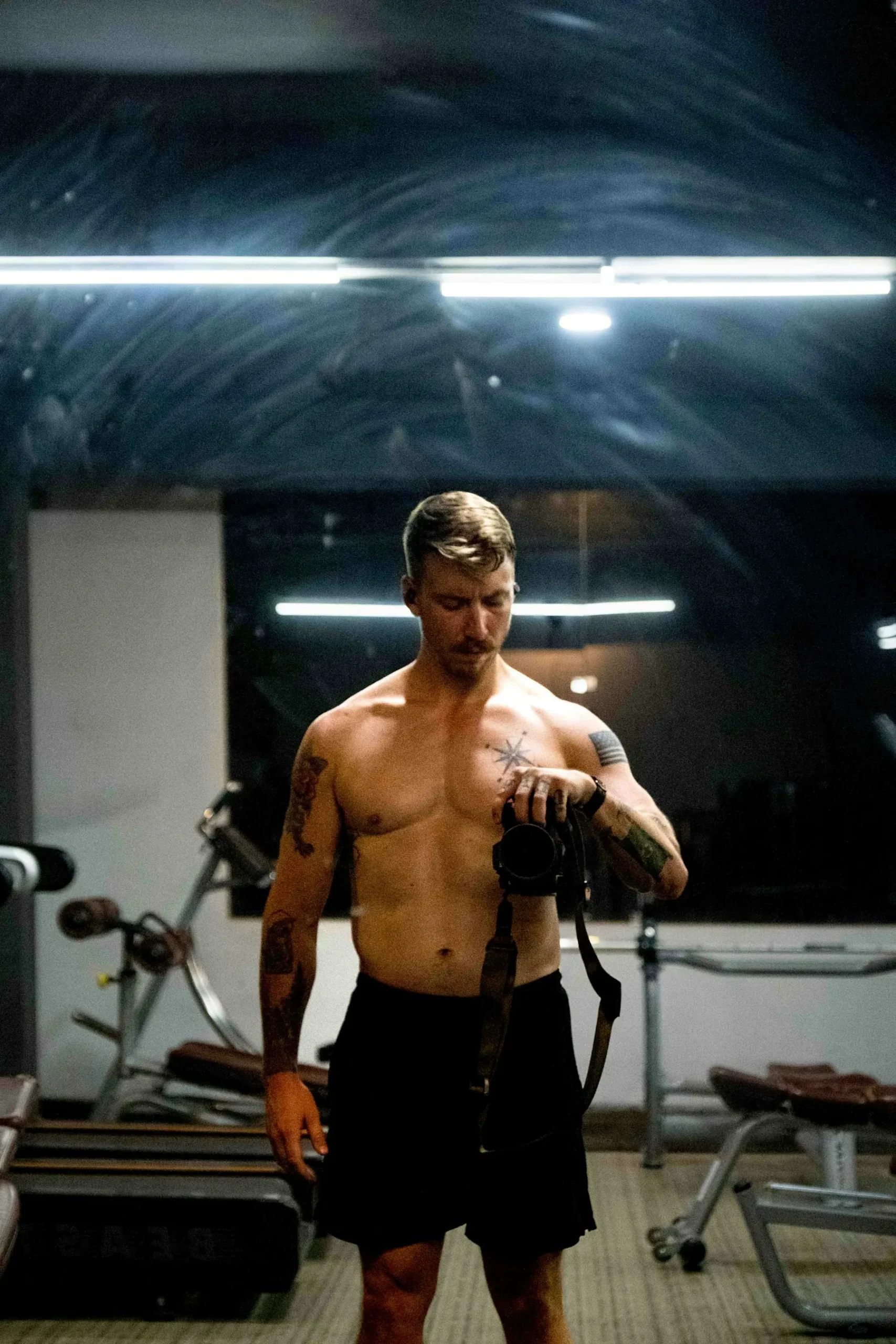 Athlete lifting dumbbells in a dark gym