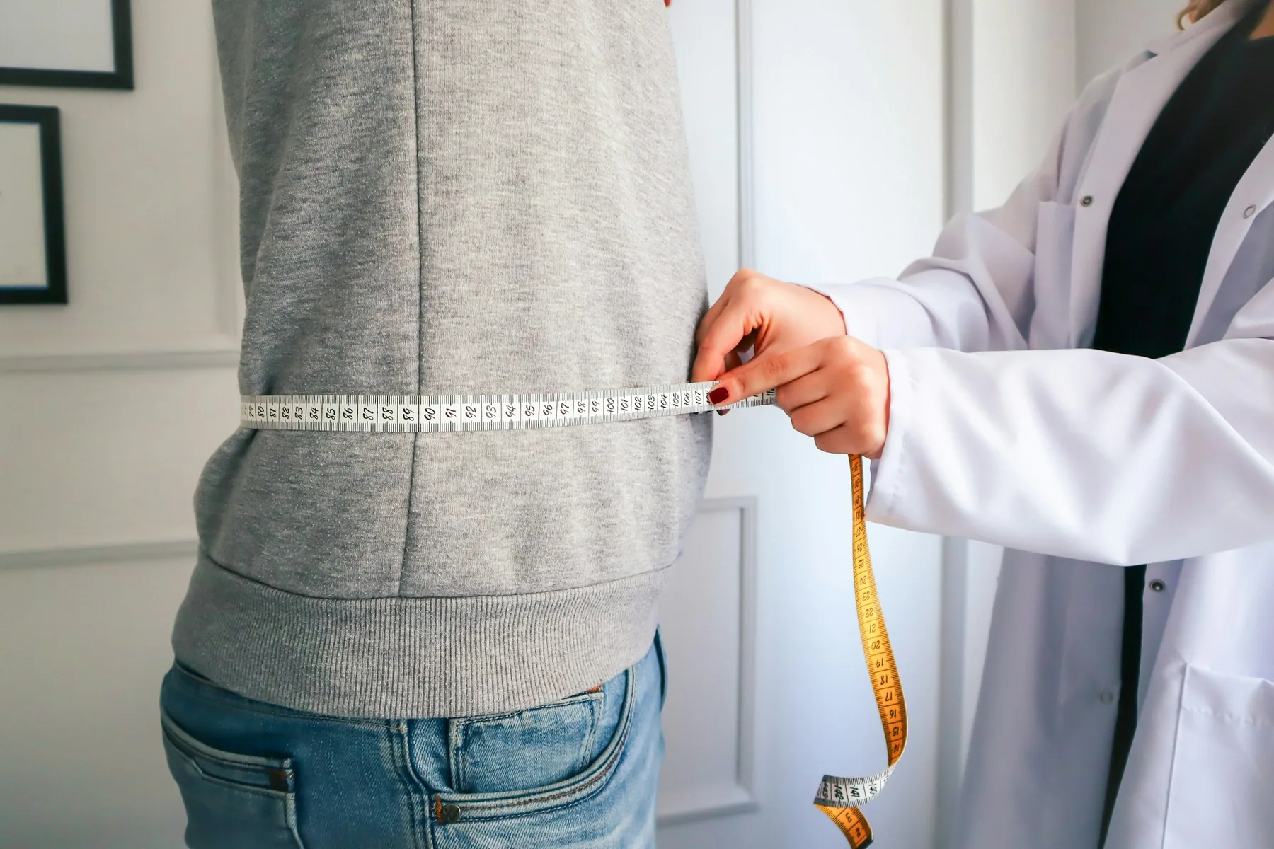 Someone measuring a waist with a tape over a training top