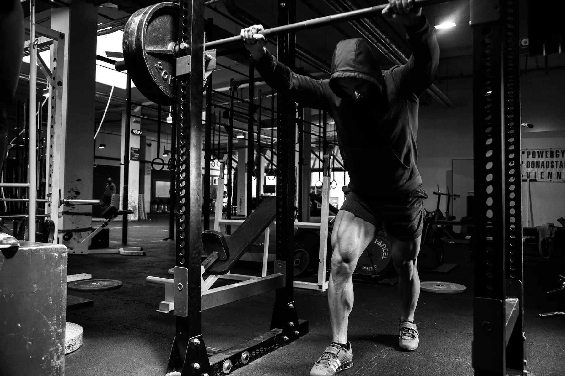 Lifter at the bottom of a barbell back squat with shorts clearing the knee