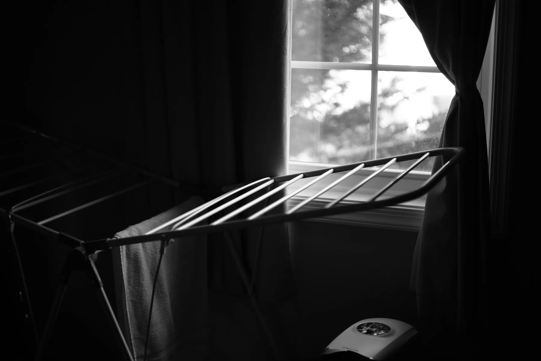 A clothes airer by a window, photographed in black and white