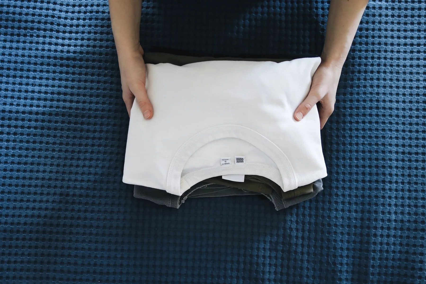 Hands folding a white t-shirt