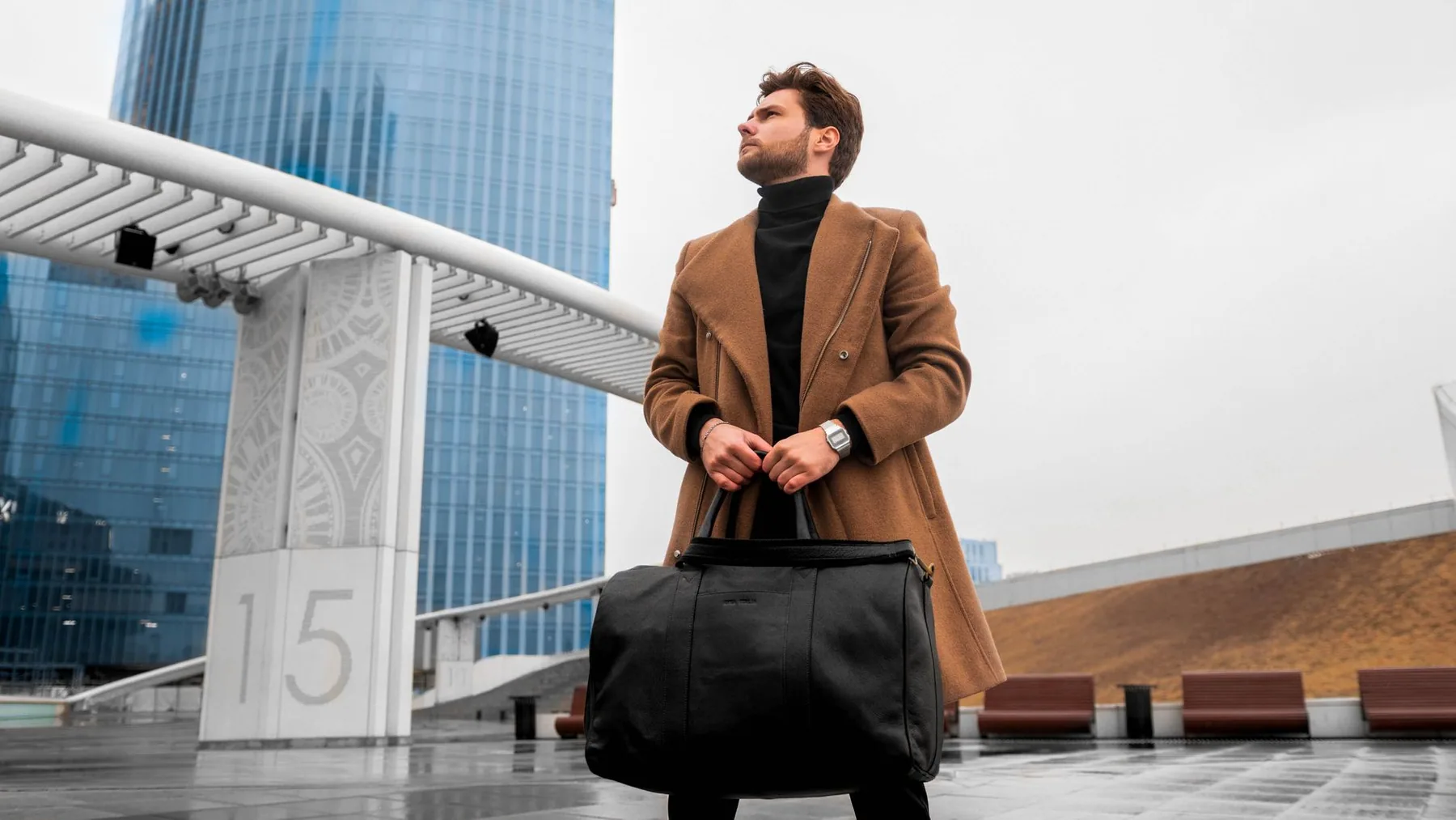 Someone carrying a plain black holdall in a city street