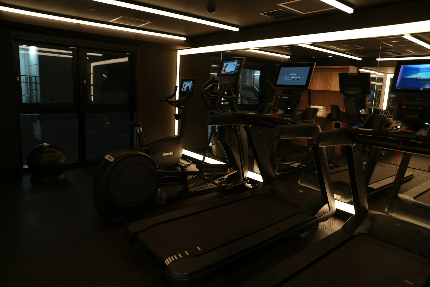 A dark hotel fitness room with cardio machines