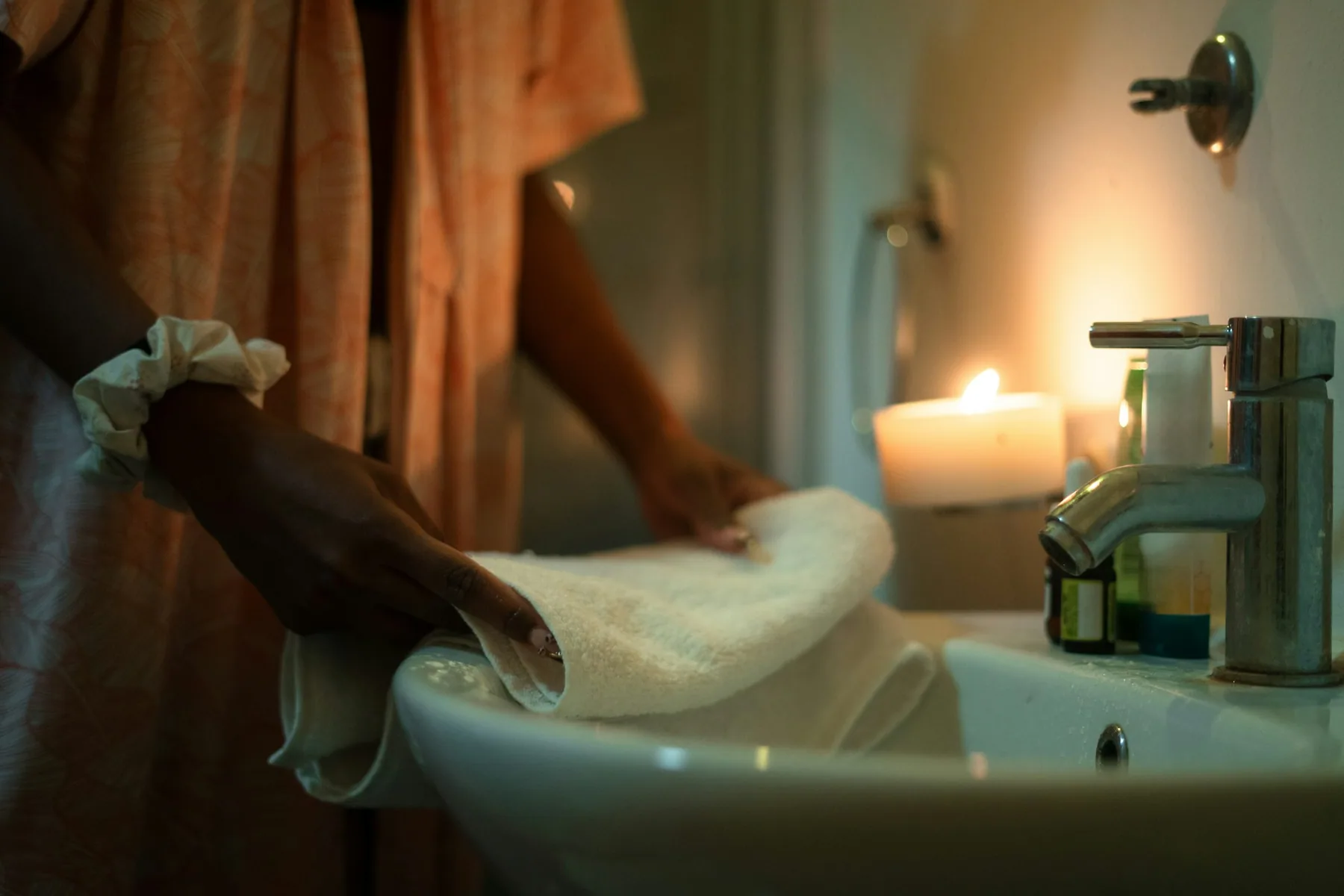 Hands lifting a pale garment out of a basin