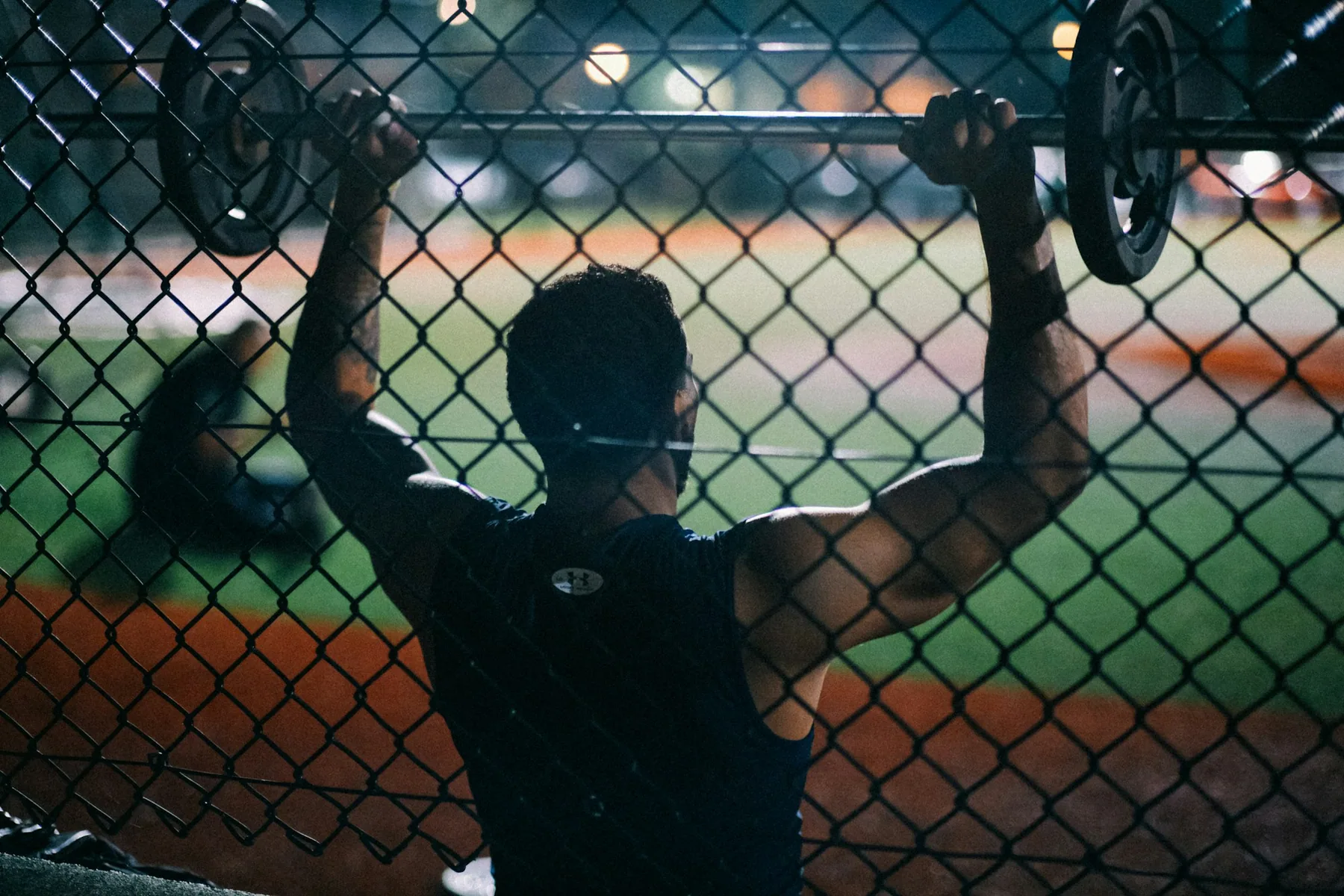 Athlete pressing dumbbells overhead, silhouetted