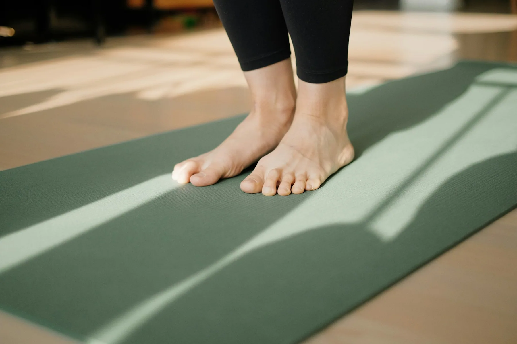 Bare feet on a mat, with a legging hem above the ankle