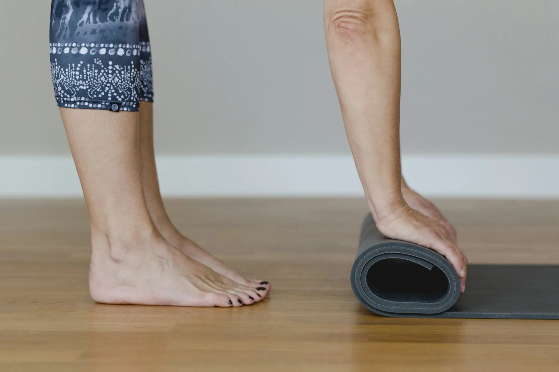Bare feet beside a mat being rolled up